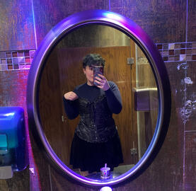 A picture of me in a bathroom mirror surrounded by blue and purple lights wearing a cute black corset and skirt
